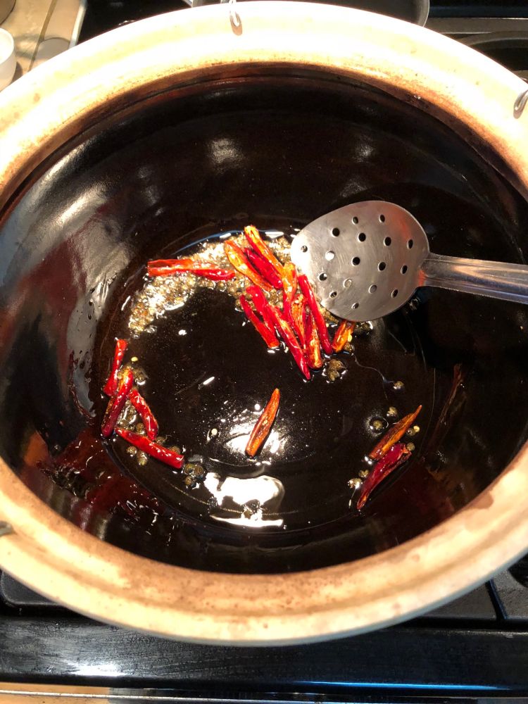 Sichuan Boiling Fish (Shui Zhu Yu) in process in a clay pot.